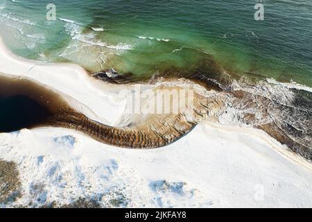 Una vista aerea delle onde del mare che si infrangono sulla riva innevata Foto Stock