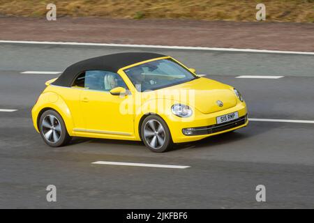 2015 giallo VW Volkswagen Beetle 1197cc 6 velocità Manuale Cabrio; in movimento, in movimento, viaggiando sull'autostrada M6, Regno Unito Foto Stock