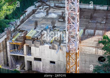 Costruzione urbana di un nuovo edificio, lavori di fondazione primaria, vista dall'alto sullo sfondo di un frammento della base di una gru a torre. Foto Stock