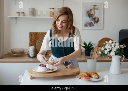 La ragazza sposta le torte su un piatto in cucina Foto Stock