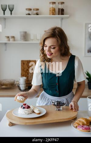 La ragazza sposta le torte su un piatto in cucina Foto Stock