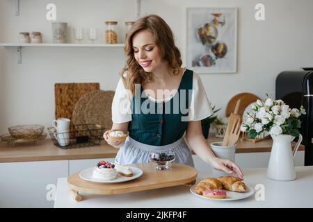 La ragazza sposta le torte su un piatto in cucina Foto Stock