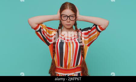 Non vuoi ascoltare e ascoltare. Frustrata irritata ragazza rossa che copre le orecchie e gesturing no, evitando consiglio ignorando rumore sgradevole voci forti. Bambino zenzero giovane su sfondo blu Foto Stock