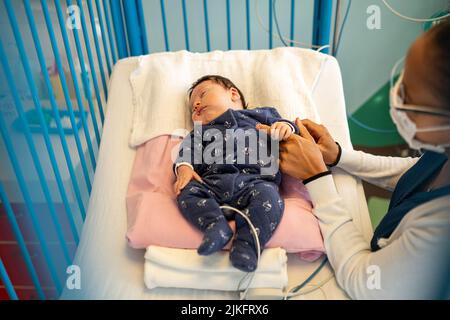 Madre e figlio con bronchiolite con infermiere in un reparto pediatrico ospedaliero. Foto Stock