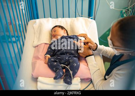 Madre e figlio con bronchiolite con infermiere in un reparto pediatrico ospedaliero. Foto Stock