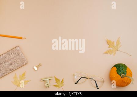 Ciao autunno concetto. Luogo di lavoro con foglie cadute, zucca, blocco note, matite, bicchieri per studenti, studentessa o blogger Foto Stock