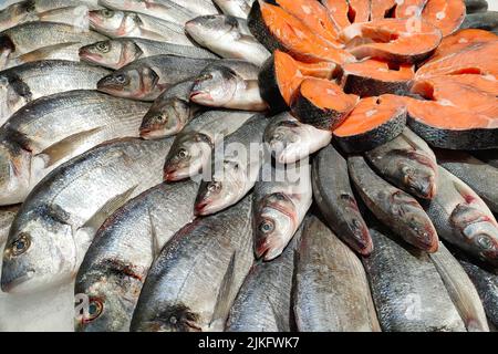 Pesce fresco fresco e filetto sul ghiaccio al banco del supermercato di pesce. Diversi tipi di pesce e di mare. Foto Stock