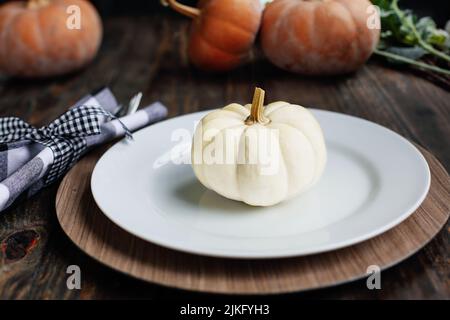 Luogo di vacanza con piatto, tovagliolo, e argenteria su un tavolo decorato giorno del Ringraziamento. Zucche bianche e arancioni. Messa a fuoco selettiva con sfocatura Foto Stock