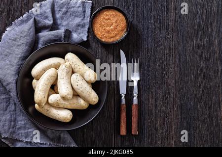 Weisswurst in ciotola nera, salsicce bianche di vitello tritato, pancetta di maiale, spezie e prezzemolo, servito con senape dolce, piatto, spazio libero Foto Stock