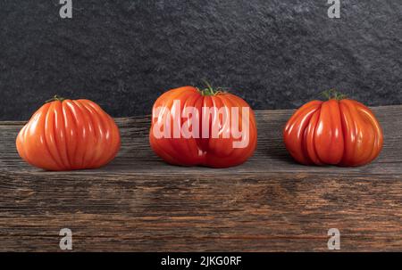 Un gruppo di grossi pomodori Costoluto su sfondo ligneo, spazio per il testo Foto Stock