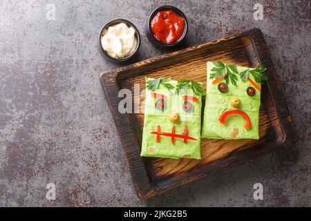 Halloween Monster avvolge burrito sandwich con faccia divertente su un vassoio di legno sul tavolo. Vista orizzontale dall'alto Foto Stock