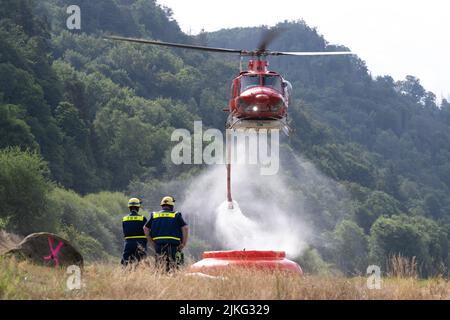 Schmilka, Germania. 02nd ago 2022. Un elicottero sorvola un bacino idrografico per raccogliere l'acqua e spegnere un incendio boschivo nel Parco Nazionale della Svizzera sassone. Credit: Sebastian Kahnert/dpa/Alamy Live News Foto Stock