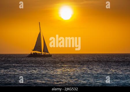 Spiaggia idilliaco con barca a vela ad Aruba al tramonto dorato, Antille olandesi Foto Stock