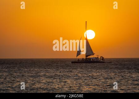 Idilliaca spiaggia caraibica con barca a vela ad Aruba al tramonto d'oro, Antille olandesi Foto Stock