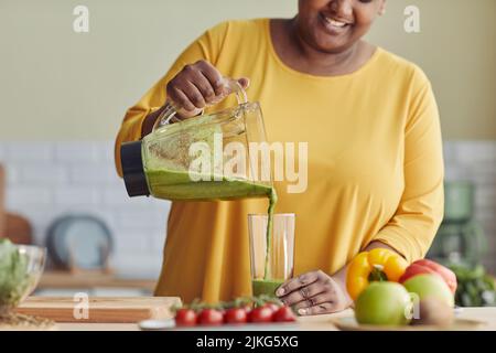 Primo piano di sorridente donna nera godendo sano frullato in cucina di casa, spazio copia Foto Stock