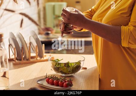 Primo piano di sovrappeso donna nera che cucina pasto sano in cucina illuminata dalla luce del sole, copia spazio Foto Stock