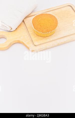 torta di carote da agricoltura biologica in una tazza di carta con farina di farro, asciugamano da cucina e tagliere in legno su un tavolo bianco Foto Stock