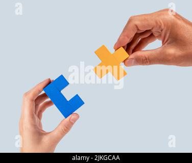 Mani uomo e donna che uniscono due pezzi di puzzle. Partnership, concetto di connessione. Comprensione reciproca, sostegno nelle relazioni. Foto di alta qualità Foto Stock