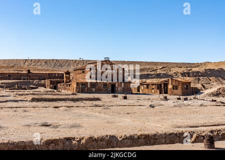 Vecchi edifici arrugginiti di fronte al cumulo di residui di scarto nel museo all'aperto delle opere di salnitro a Humberstone, Cile. Foto Stock