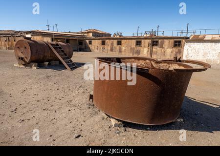 Vecchi tini arrugginiti e una caldaia a vapore nel museo all'aperto delle opere di salnitro a Humberstone, Cile. Foto Stock