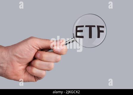 Acronimo ETF attraverso lente di ingrandimento in mano maschio. Foto Stock