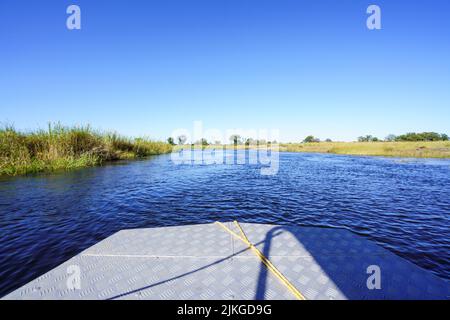 Piccola barca safari che naviga nelle acque del fiume Kwando. Parco Nazionale di Bwabwata, Namibia, Africa Foto Stock