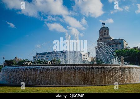 Piazza Catalogna, conosciuta anche come Plaza Catalunya, la piazza della città di Barcellona, è vista in una giornata estiva con fontane e cielo blu chiaro Foto Stock