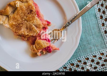 Torta di rabarbaro su piatto bianco con placemat verde chiaro e con crostata di menta Foto Stock