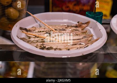 Boqueron marinato nell'aceto con olio d'oliva e prezzemolo tritato su un piatto bianco. Foto Stock