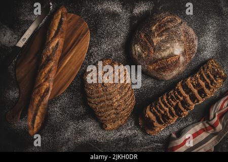 Una vista dall'alto di un assortimento di pane appena sfornato su un tavolo nero Foto Stock