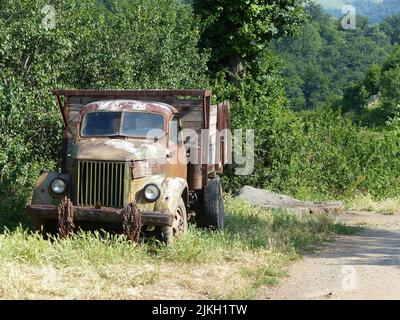Un vecchio camion GAZ parcheggiato fuori dalla strada con una vista della foresta sullo sfondo Foto Stock
