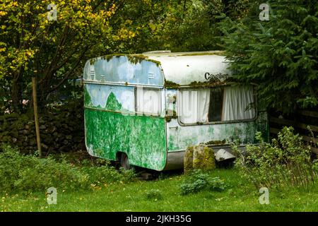 Una vecchia carovana verde abbandonata in un parco Foto Stock