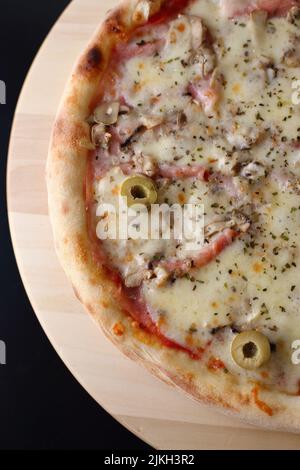 Una vista verticale dall'alto di una pizza con mortadella, olive, funghi e condimenti di formaggio Foto Stock