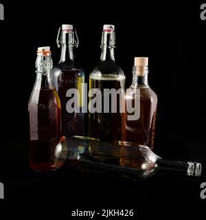 Un primo piano verticale di bottiglie pronte per il riciclaggio riempite con acqua e coloranti alimentari su fondo nero Foto Stock