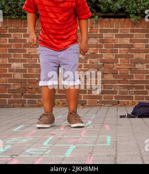 Ragazzo filippino che gioca hopscotch nel parco giochi della scuola. Torna al concetto di scuola. Gruppo di bambini multietnici Foto Stock