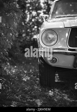 Un'immagine verticale del faro anteriore sinistro di una Ford Mustang cabriolet classic car Foto Stock