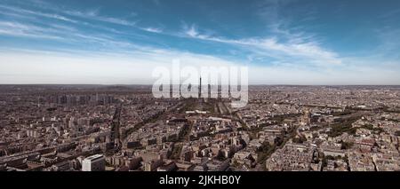 Un'immagine panoramica di Parigi con i suoi densi edifici e la Torre Eiffel nel mezzo sotto il cielo blu Foto Stock