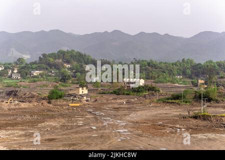 Un terreno roccioso tumble-down con alcuni edifici sullo sfondo di montagne boschive Foto Stock