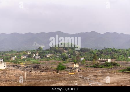 Un terreno roccioso tumble-down con alcuni edifici sullo sfondo di montagne boschive Foto Stock