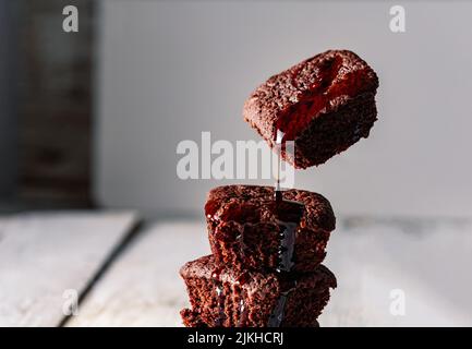 Una deliziosa torta di brownie al cioccolato si sfalda l'una sull'altra con salsa di cioccolato che cade su di essa Foto Stock