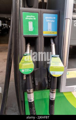 Un primo piano verticale di pistole di rifornimento, verde e blu con diversi tipi di carburante Foto Stock