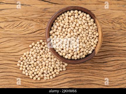 Fagioli di soia non cotti in una ciotola sopra tavola di legno. Foto Stock