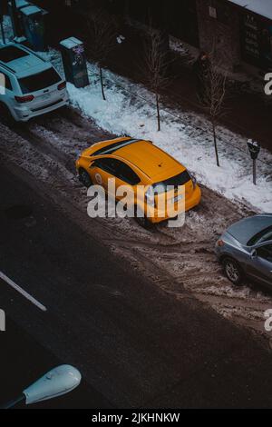 Un colpo verticale di una Toyota gialla parcheggiata in strada durante l'inverno a Vancouver, Canada Foto Stock