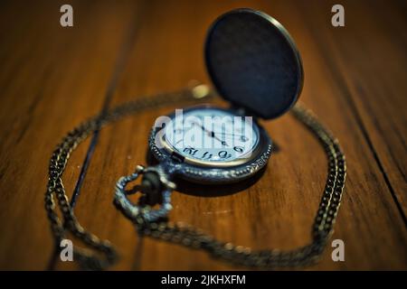 Un primo piano di un vecchio orologio tascabile al quarzo su un tavolo di legno Foto Stock