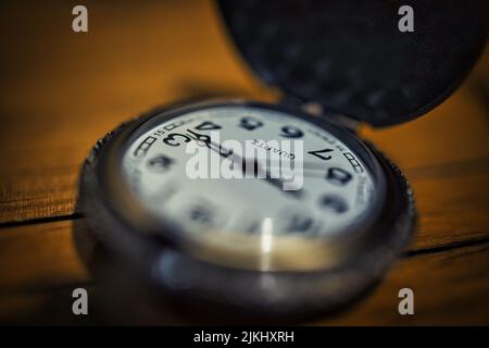 Un primo piano di un vecchio orologio tascabile al quarzo su un tavolo di legno Foto Stock