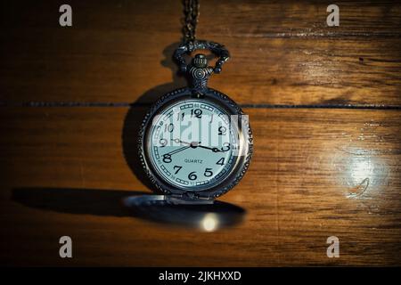 Un primo piano di un vecchio orologio tascabile al quarzo su un tavolo di legno Foto Stock