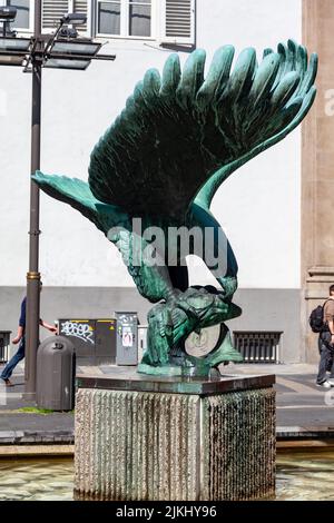 Uno scatto verticale di una statua di bronzo di un'aquila che mangia un pesce nel centro di Anversa, Belgio. Foto Stock