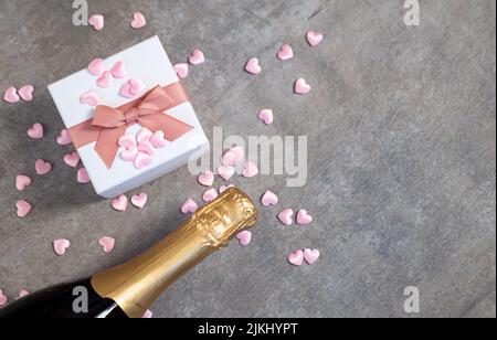 San Valentino sfondo con cuori, confezione regalo, champagne. Sullo sfondo della tavola in pietra grigia, vista dall'alto Foto Stock