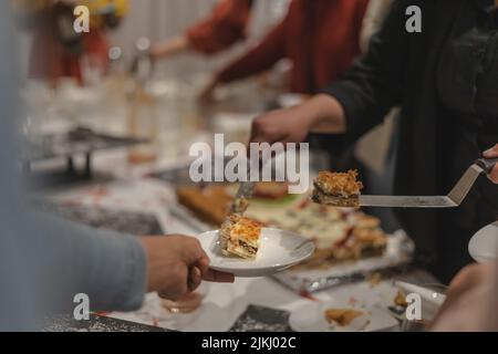 Donna che mette la fetta di torta in un piatto al coperto Foto Stock