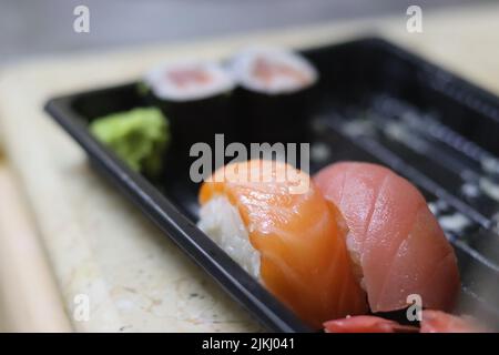 Un'inquadratura selettiva di gustoso sushi al salmone su plastica nera con sfondo sfocato Foto Stock